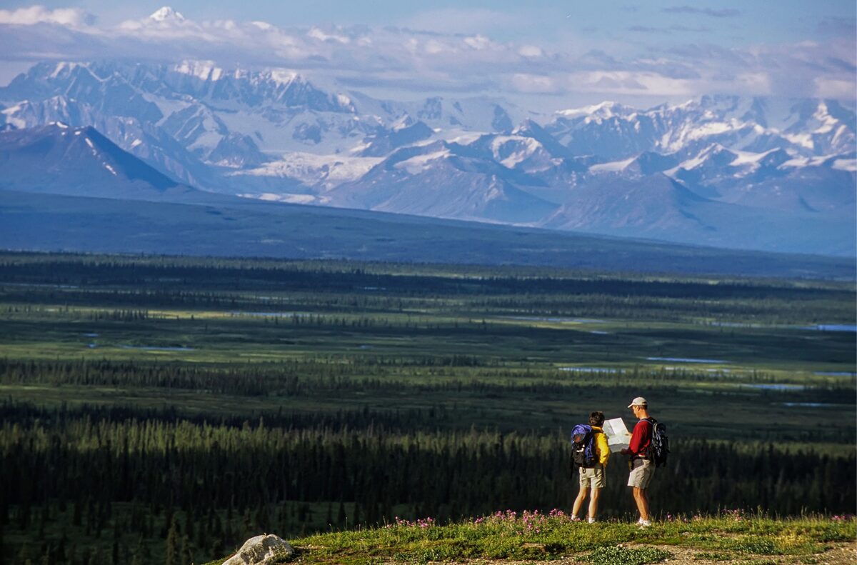 Hikers looking at a map while taking in the view of the Alaska Range in the distance. Nikon F5, AF-S NIKKOR 70-200mm f/2.8E FL ED VR, Fujichrome Provia 100F. Exposure: 1/250 sec., ƒ/8.