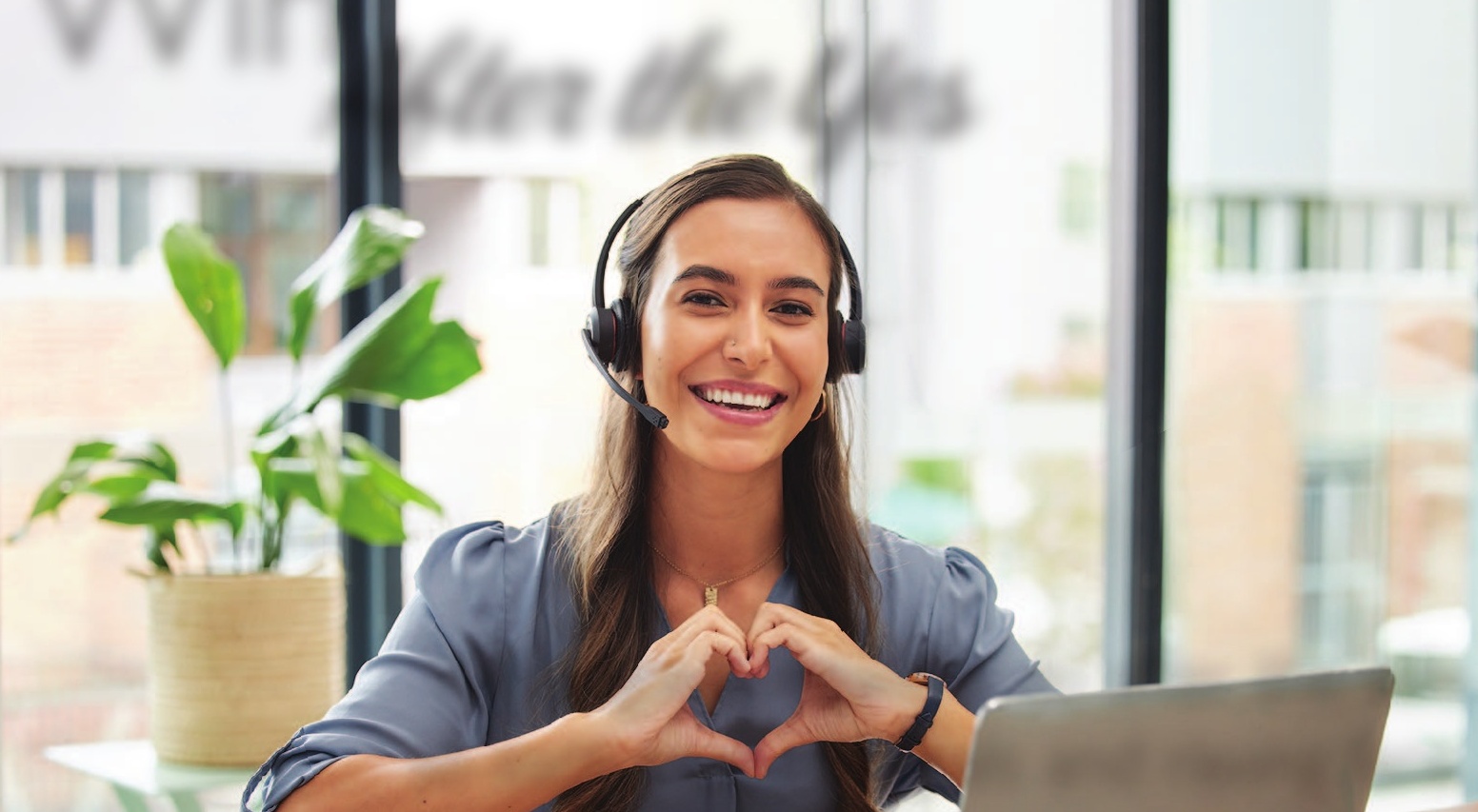 a woman wearing headphones making a heart with her hands