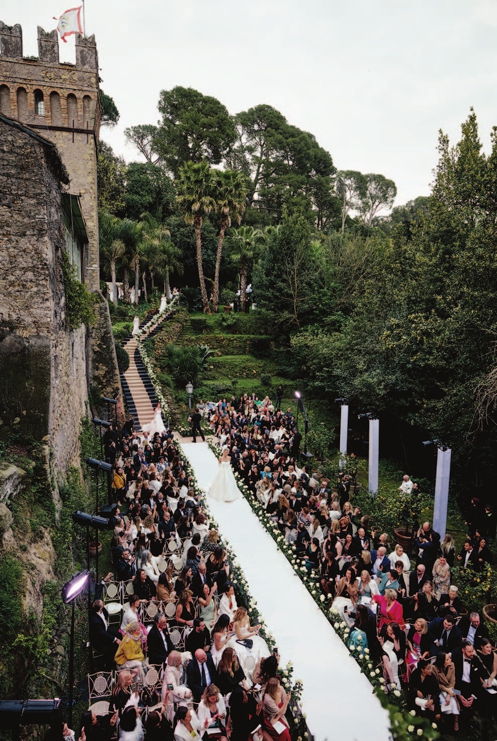 a group of people walking down a path with a woman in a white dress